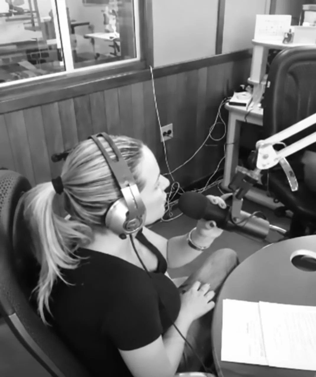 Dra. Cinthya Andrade, de fones de ouvido, falando ao microfone no estúdio da Autêntica FM